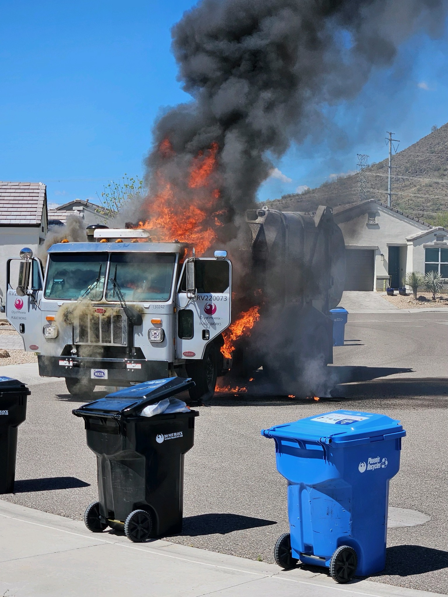 A Phoenix garbage truck with flames coming out from behind the cab.